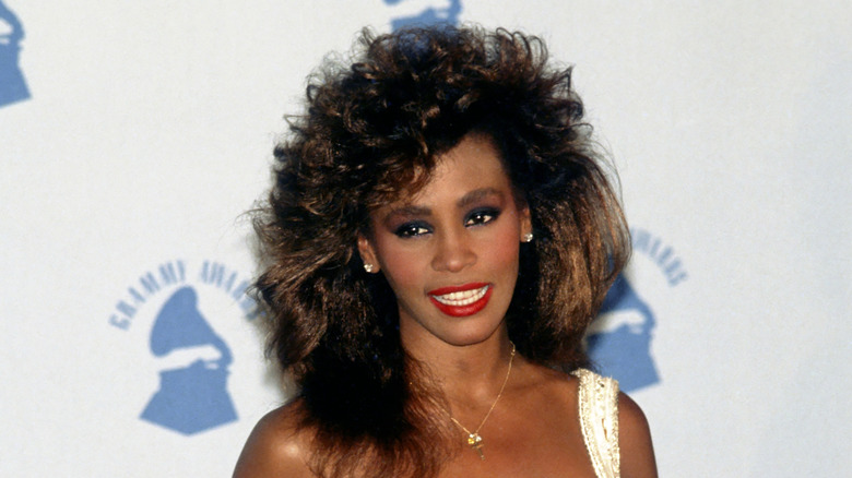 whitney houston with big hair at a grammy ceremony in the 1980s