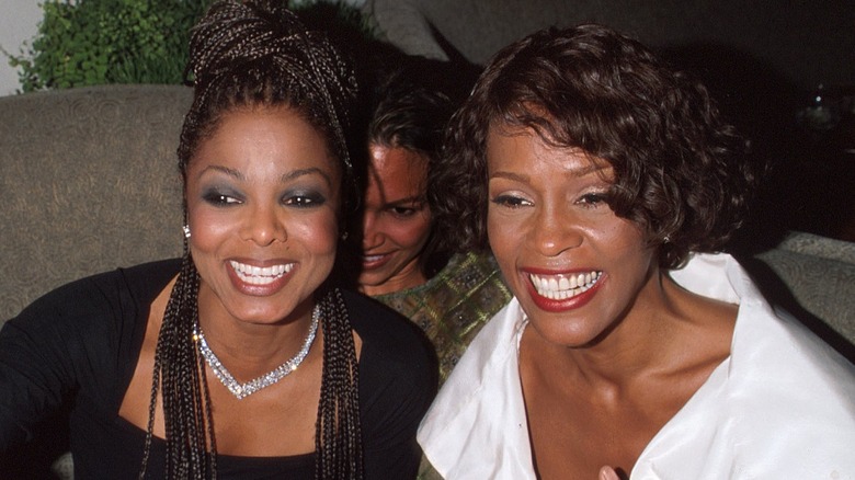 whitney houston sitting and smiling with janet jackson