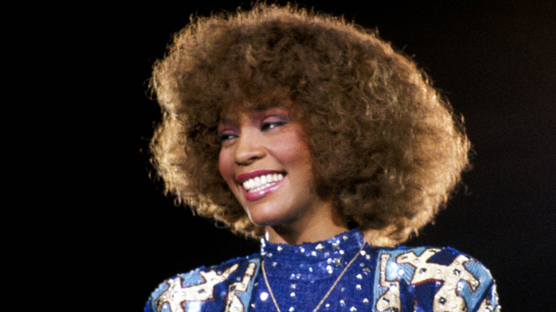 whitney houston with big hair in 1980s looking to the side