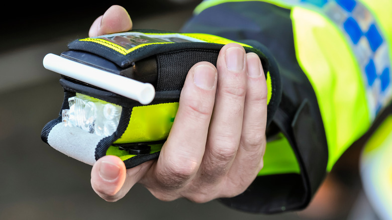 A hand holding a roadside breathalyzer