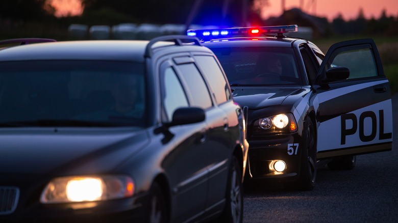 A vehicle at night getting pulled over by police car