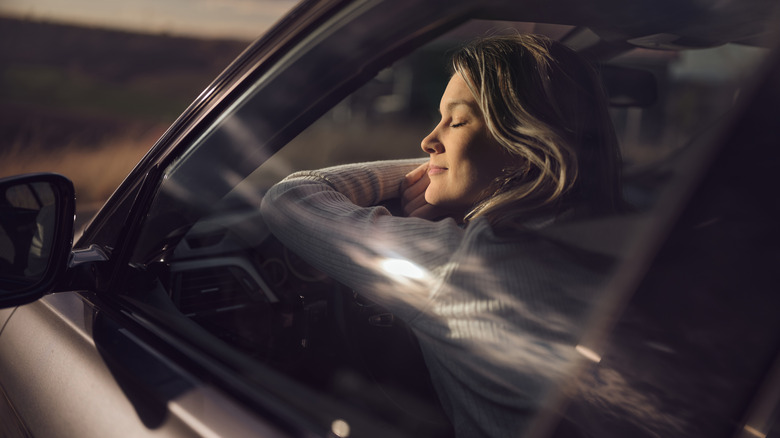 A woman peacefully sleeping behind the wheel of a car