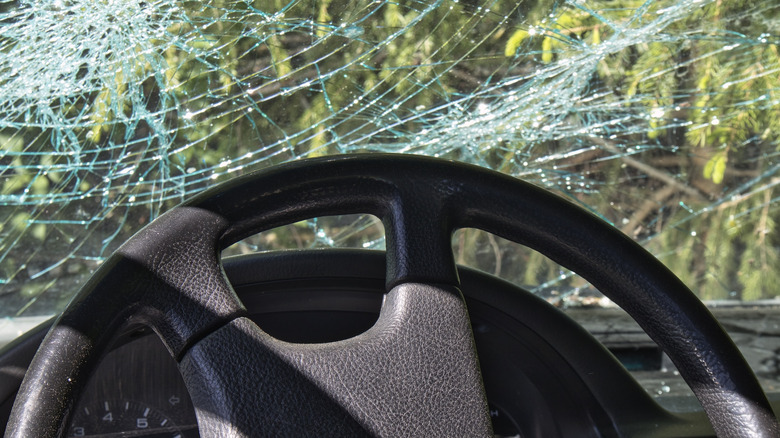 A shattered windshield with steering wheel in foreground