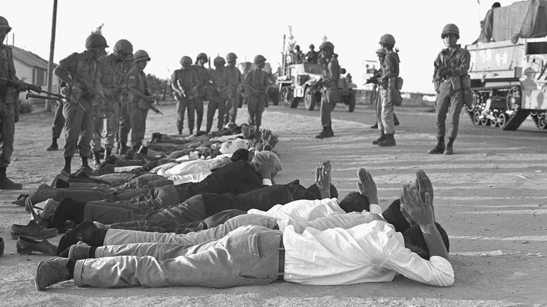 soldiers pointing guns at prisoners