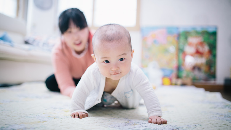 Mother playing with crawling baby