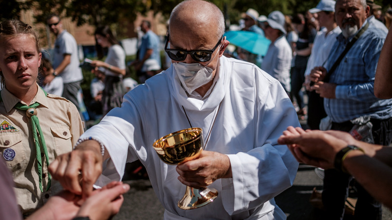 Priest giving communion, Hungary