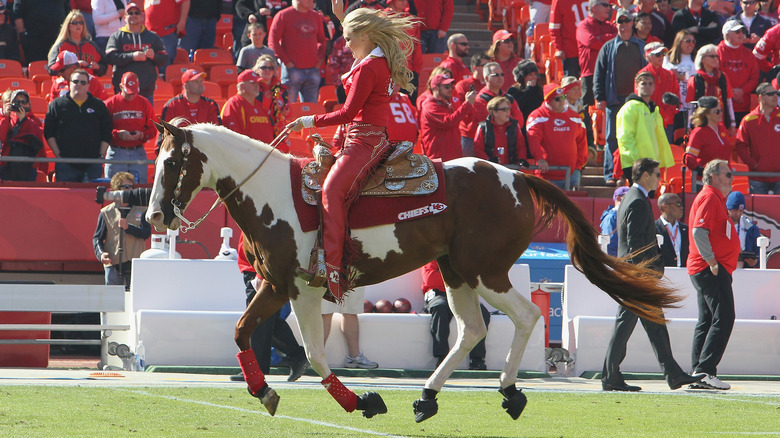 cheerleader riding Kansas City Chiefs mascot Warpaint