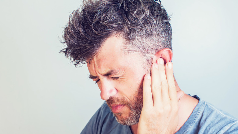 A man holding his ear in pain