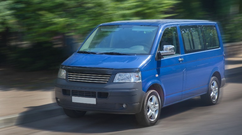 Blue van driving down road