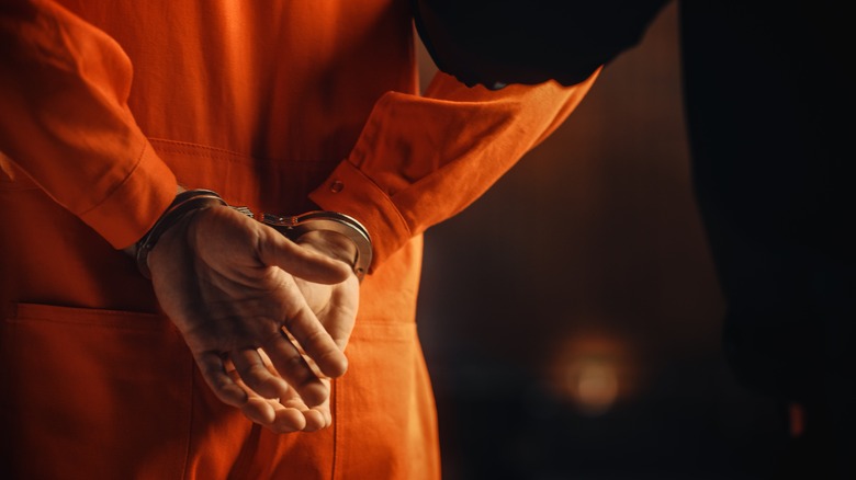 handcuffed man in orange jumpsuit