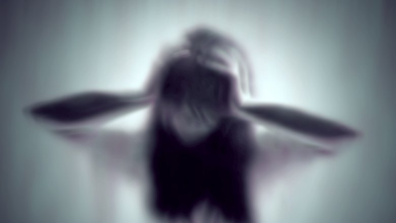 blurry image of woman with hands on head