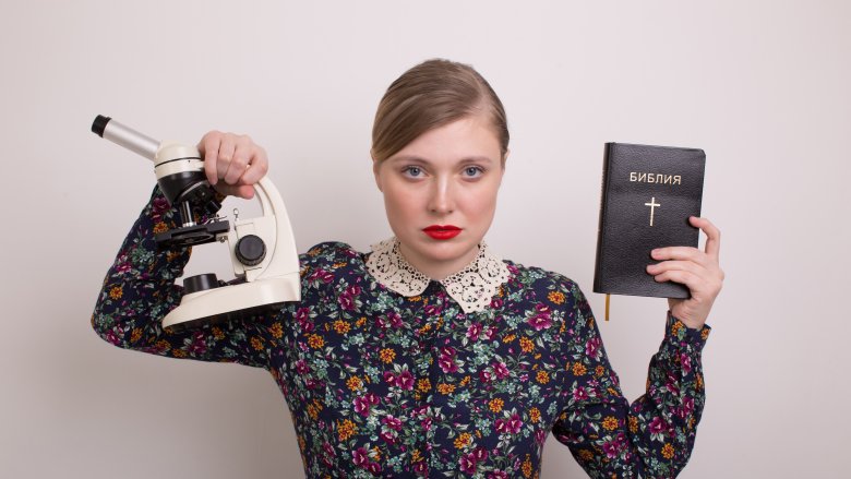 woman holding Bible and microscope 