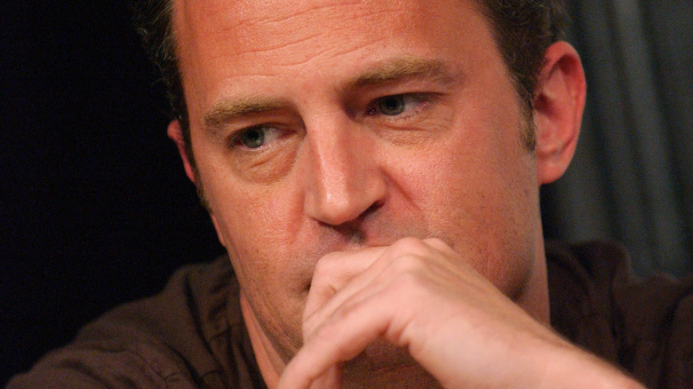 Matthew Perry looks down hand mouth