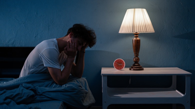 Man sitting up in bed in dark