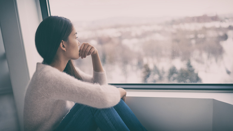 Woman looking out of window at snowy landscape