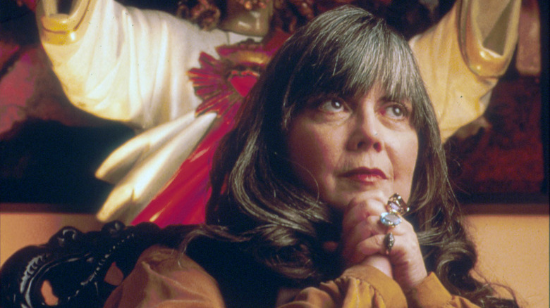 Anne Rice poses in front of a statue of Christ