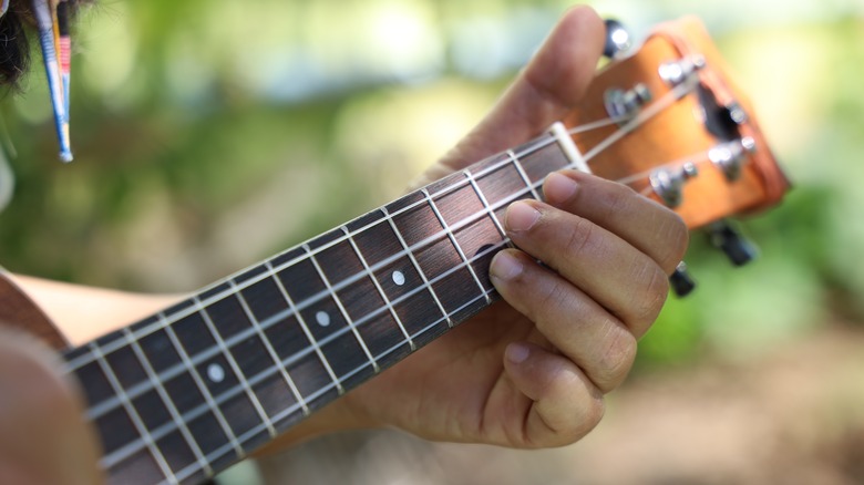 close-up person playing ukulele