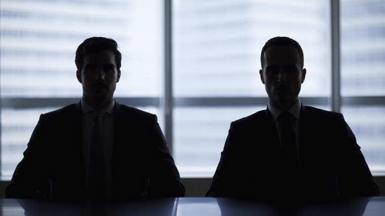 two men silhouetted while sitting at table