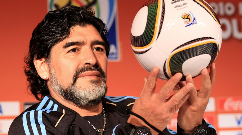 Diego Maradona holding up a ball at a press conference