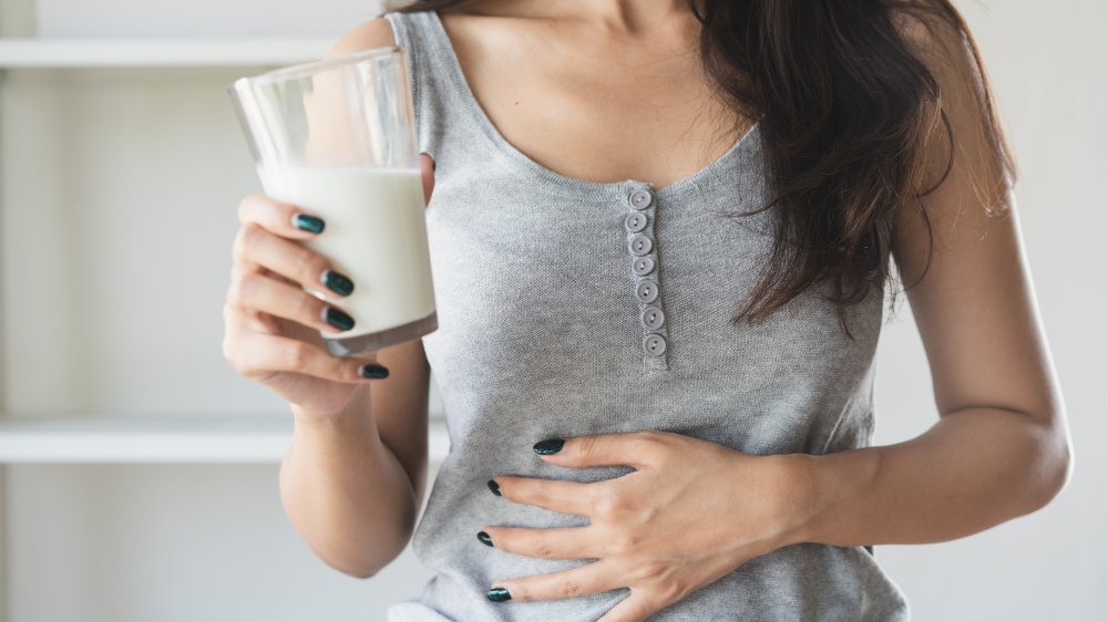 Woman holding a glass of milk and having a stomachache.