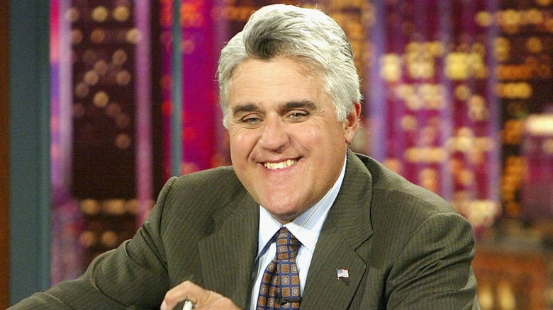 Jay Leno hosting The Tonight Show at desk and smiling