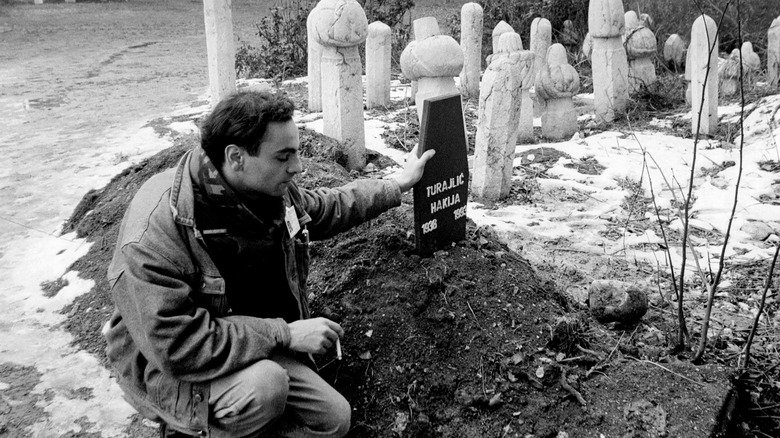 Man kneeling holding Hakija Turajilic's tombstone