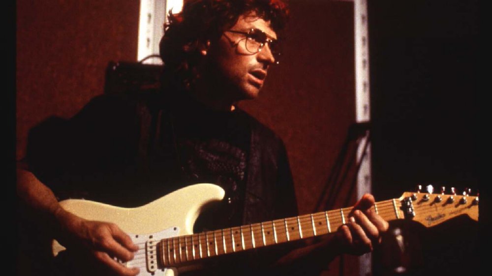 Tim Daly plays a guitar as David Koresh