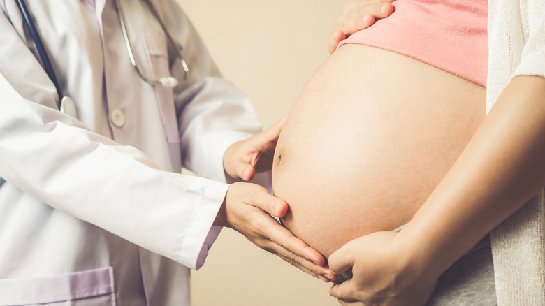 Doctor gentle touches a pregnant woman's belly