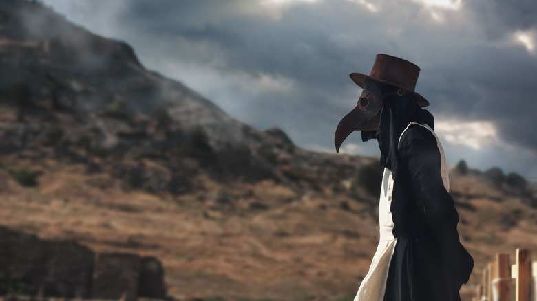 Plague doctor walking through hillside