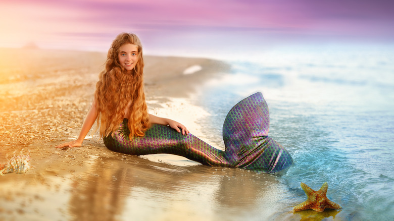 blonde mermaid sitting on the shore