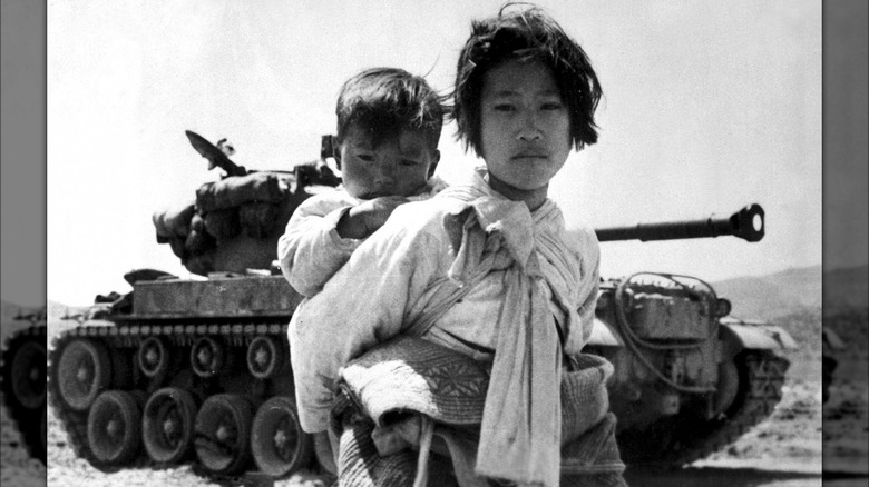 Korean woman carrying baby near tank