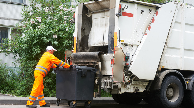 Worker loading waste and trash bin