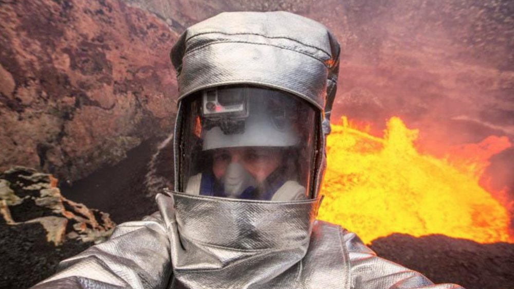 dangerous social media photo, man in heatproof suit standing in front of an active lava pool