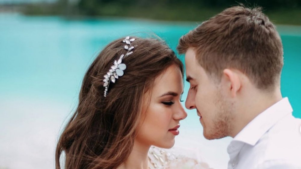 dangerous social media photo, bride and groom posing in front of bright blue lake