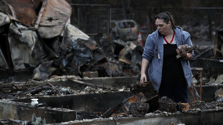 burned house woman picking through rubble