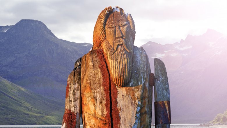 wooden statue of Odin in front of mountain