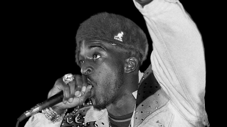 Rakim performing mic white jacket hat