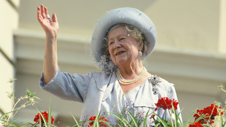 Elizabeth, the Queen Mother waving from behind flowers