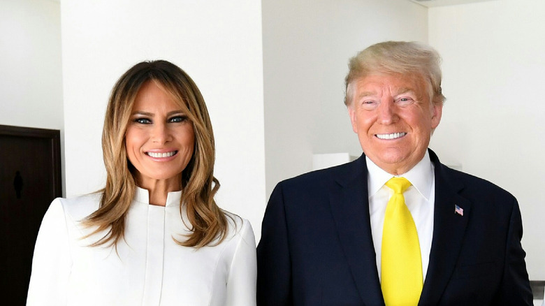 Donald and Melania Trump next to each other with forces smiles