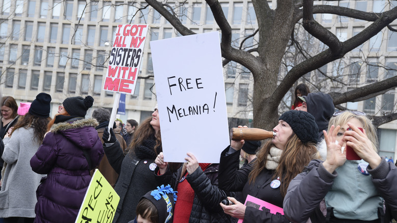 Women holding a sign reading "Free Melania" at a march