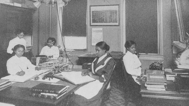 Women sat at desk with ledgers