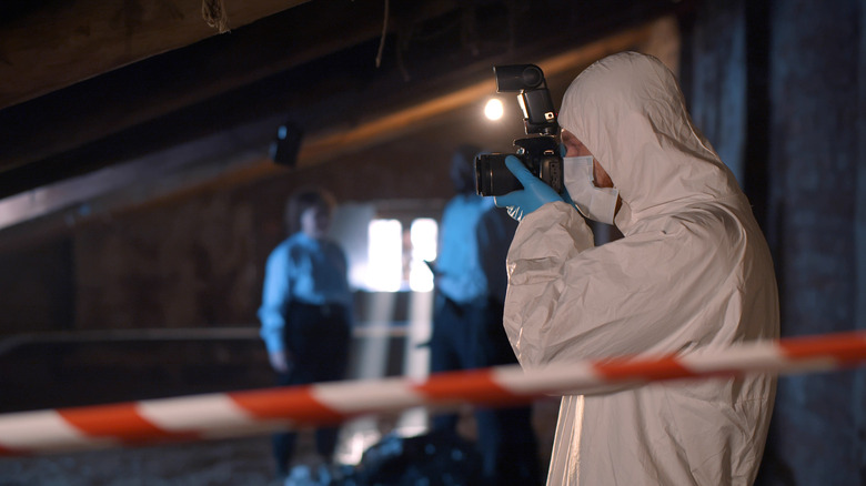 Crime scene investigator taking photos white coveralls