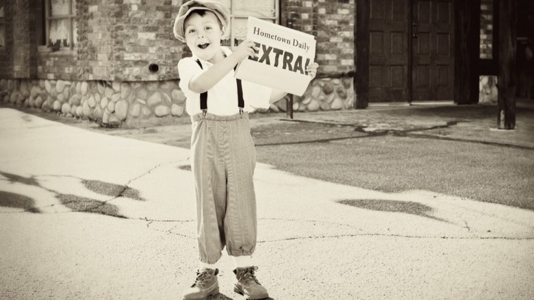 Newsboy holding extra edition of newspaper