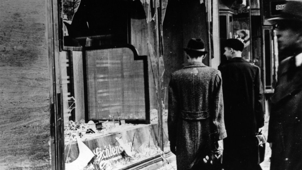 Shoppers walking past a shop destroyed during Kristallnacht