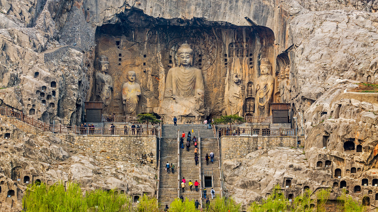 People scaling stairs to Buddha statue