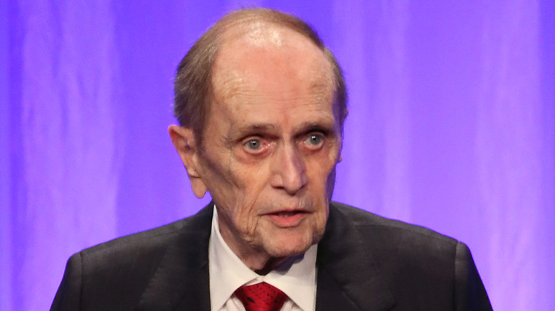 Bob Newhart suit talking event purple background