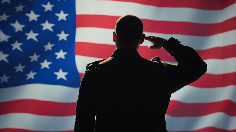 Military person saluting American flag