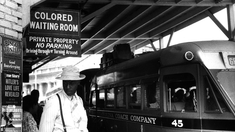 man standing by train under sign