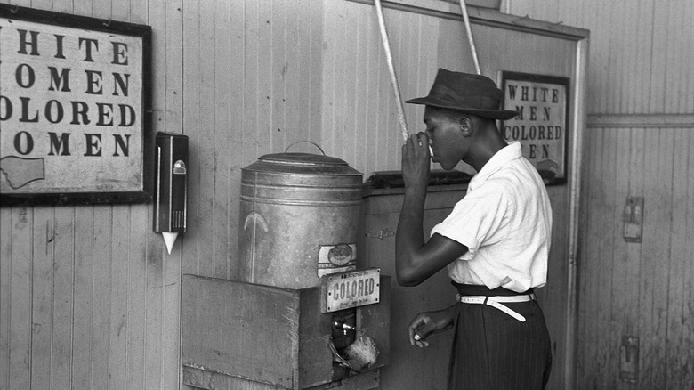 man drinking at segregated water fountain