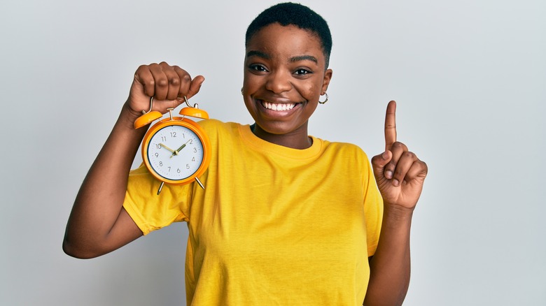 happy woman holding an alarm clock